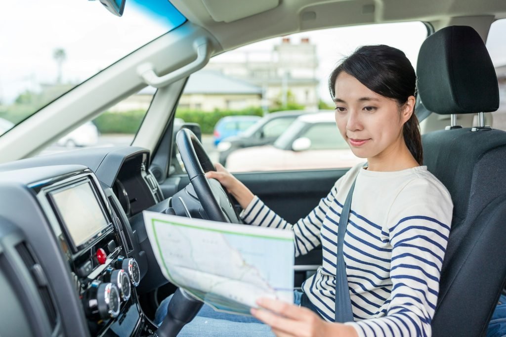 Woman driving car and using map